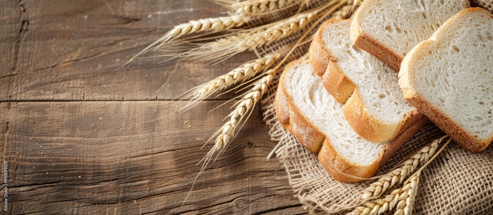 Aufkleber Copy space image of white bread slices and wheat ears displayed on burlap over a rustic wooden surface