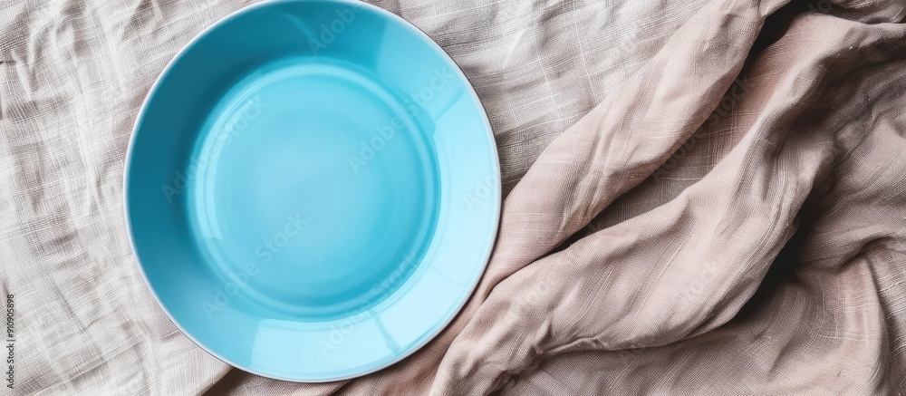 Leinwandbilder Top view of an empty blue plate on a tablecloth with a napkin and copy space image for your design