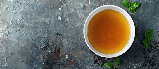 A healthy food moment captured from above with a bowl of broth on a gray background providing ample copy space in a panoramic banner image