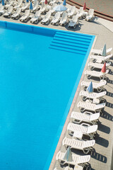 swimming pool with sun beds and blue water.