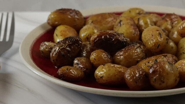 gros plan sur des Pommes de terre grenaille au thym et &agrave; l'ail dans une assiette	
