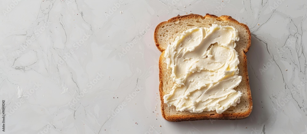 Poster Top down view of a slice of bread spread with delicious cream cheese on a white marble surface with room for text in the image s background. Creative banner. Copyspace image