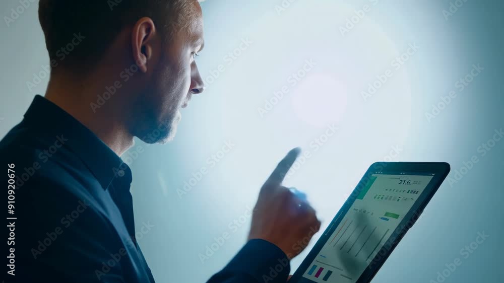 Poster a man in dark clothes stands with a tablet in his hands, on which graphs and data are displayed. he 