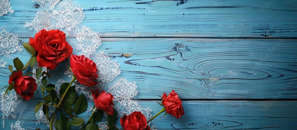 Poster top view of red flowers on a lace tablecloth over a blue wooden table with copy space image