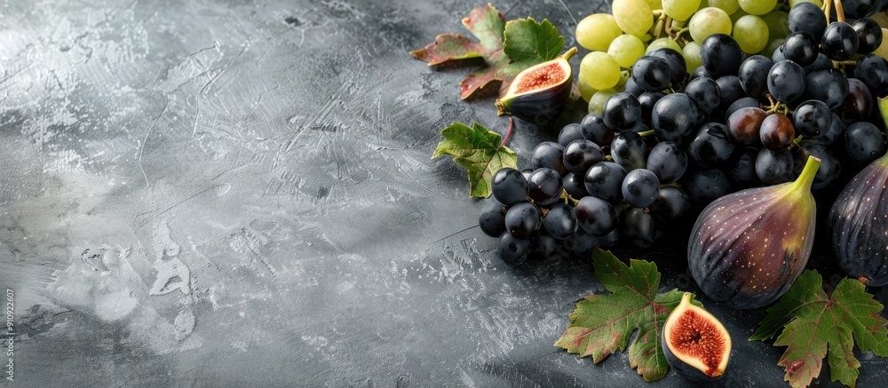 Aufkleber fresh autumn fruits such as black and green grapes figs and leaves displayed on a grey table with a 
