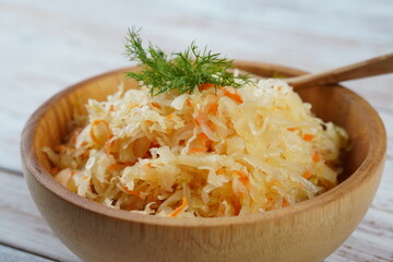 Bowl of tasty sauerkraut on white wooden table. Sour cabbage top view