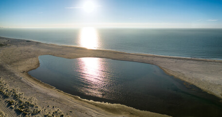 Aerial photo of the sun and reflection in the North Sea on the Zandmotor beach of Kijkduin, The Hague in the late afternoon.