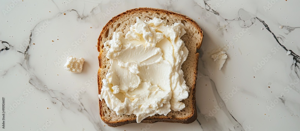 Poster Top down view of a slice of bread spread with delicious cream cheese on a white marble surface with room for text in the image s background. Creative banner. Copyspace image