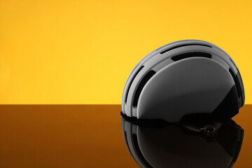 Fototapeta premium White protective helmet on mirror surface against orange background. Space for text