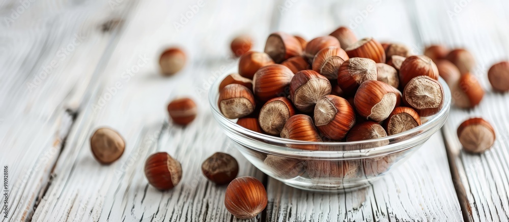Poster hazelnuts without shells in a glass bowl on a white wooden surface exemplifying healthy eating with 