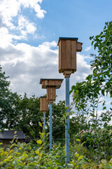 Large birdhouses located on metal poles. Wooden birdhouses against a blue sky.
