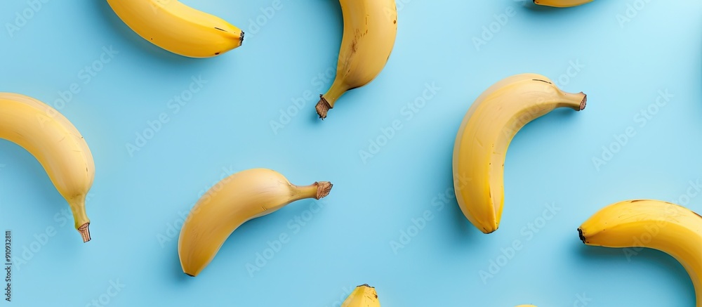 Poster Top view of a healthy and simple raw food concept with a banana pattern on a blue background in a flat lay style shot with copy space image