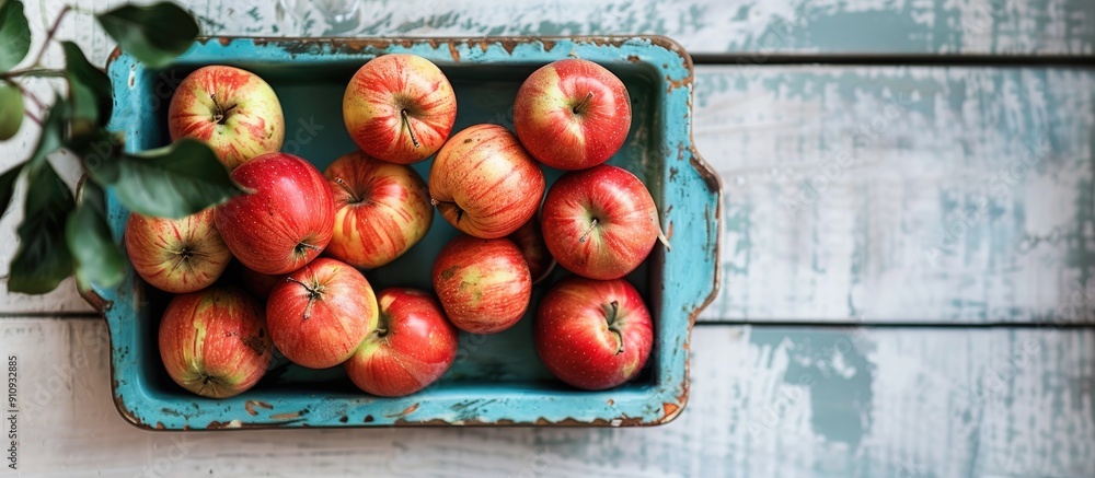 Poster fresh apples arranged neatly on a blue tray on a rustic white wooden table providing a scenic copy s
