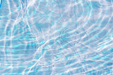 Blue water with ripples on the surface. Defocus blurred transparent blue colored clear calm water surface texture with splashes and bubbles. Water waves with shining pattern texture background.