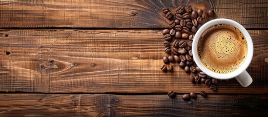 Wooden background with a cup containing espresso or Americano accompanied by coffee beans offering copy space for displaying images