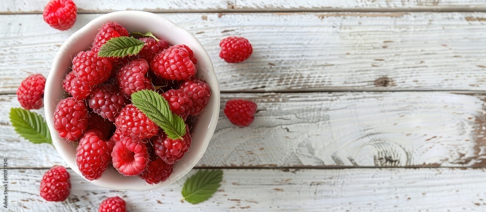 Poster Fresh red raspberries displayed in a white bowl on a light rustic wood backdrop in a top view image with available copy space and selective focus for a vegetarian context