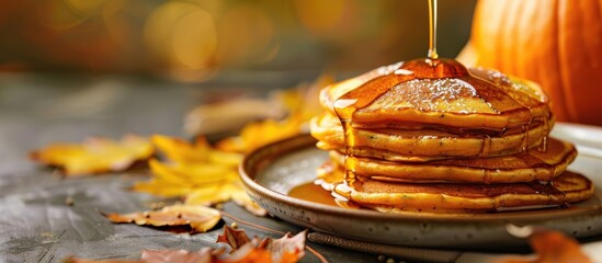 Selective focus on pumpkin pancakes with syrup on a plate placed on a table with copy space image available