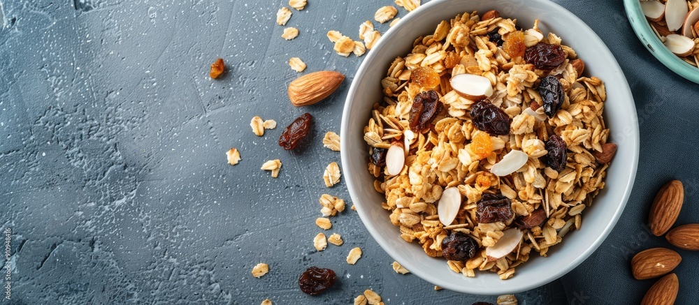 Poster flat lay overhead view of a bowl of homemade granola with raisins and almonds suitable for adding te