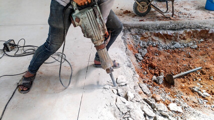 construction worker using heavy-duty tool and breaking reinforced concrete