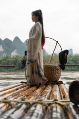 Young Chinese Hanfu woman looking down at bamboo raft by Li River in Xingping. Close up