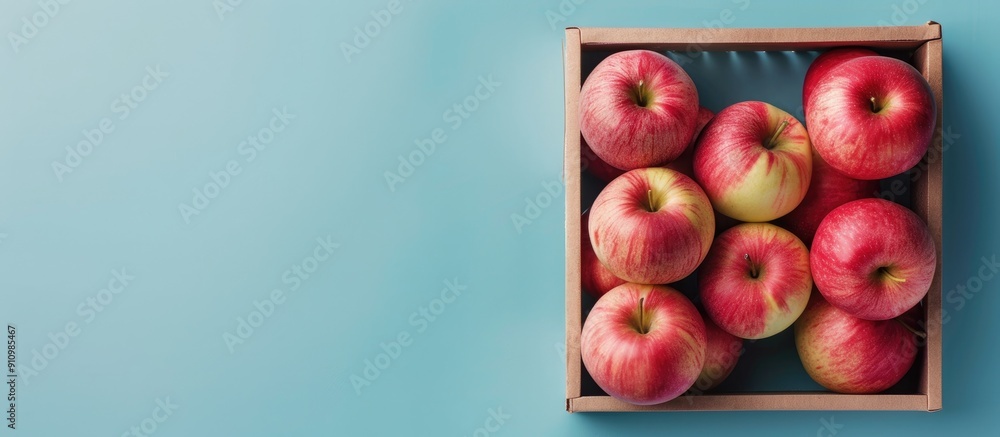 Poster pink apple beautifully arranged in a box against a blue background with copy space image