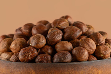 Hazelnuts in a wooden bowl close-up. Heap of whole, shelled nuts of filbert, ready to eat as snack, emphasis on detail, high resolution.