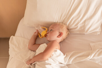little boy toddler lying in bed drinking water from bottle