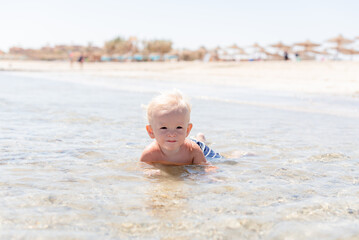 happy little boy baby blond swims in tsea