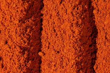 Abstract terracotta striped background of scattered paprika seasoning