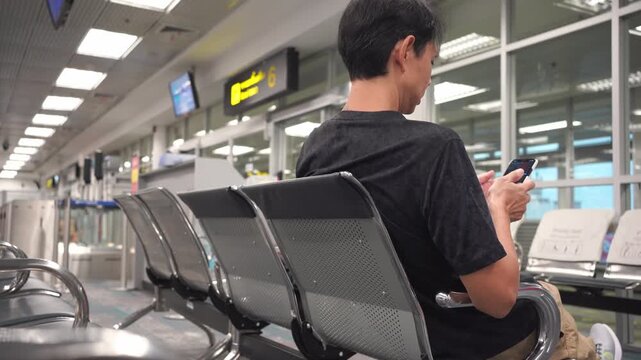 business concept with asian man sit on chair and work with tablet in airport 