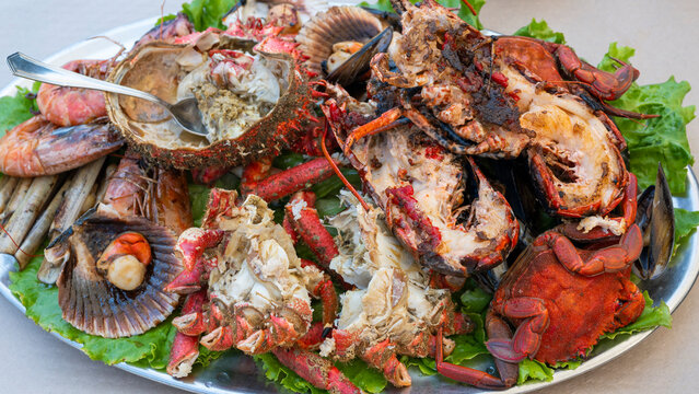 Una fuente de metal con hojas de lechuga y mariscada de marisco a la parrilla en un restaurante de Tazones, Espa&ntilde;a