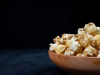 half shot of pile of popcorn in wooden bowl isolated black background