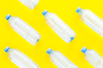 Pure water in plastic bottles on yellow background top view patt
