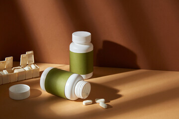 High angle shot designing template for advertising poster of vitamin or supplement product. Mock up bottle without label placed on yellow tabletop with a yellow pill box. Blank space for designing