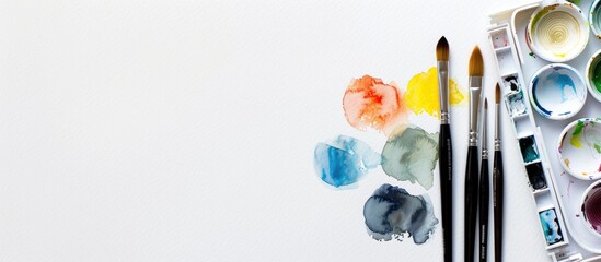 Watercolor palette and paintbrush set displayed against a white backdrop with a clear area suitable for insertion of text or graphics, like a copy space image.