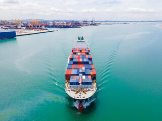 the aerial perspective of a cargo ship being loaded and unloaded at a bustling seaport and sailing out of the mainland