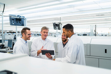 Team of competent electrical technicians in lab coats having meeting in electronics factory