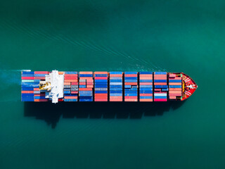 the aerial perspective of a cargo ship being loaded and unloaded at a bustling seaport and sailing out of the mainland
