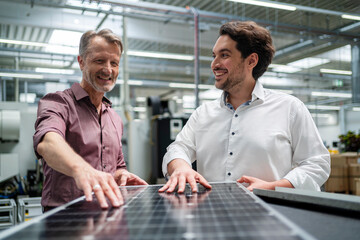 Happy engineers with solar panel at factory