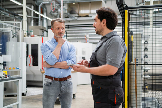 Senior manager planning with colleague standing on production floor at home