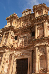 Obraz premium Historic Baroque church facade with detailed stone carvings and large wooden door in Gumiel de Izán, Spain 