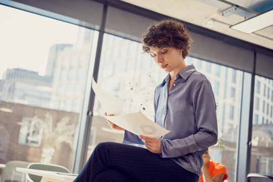 Businesswoman reading documents sitting at office