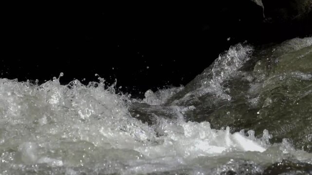 Close up of crystal clear river water rushing over stones with white foam and bubbles. Fast flowing stream with fresh natural texture. Nature, energy, freshness concept