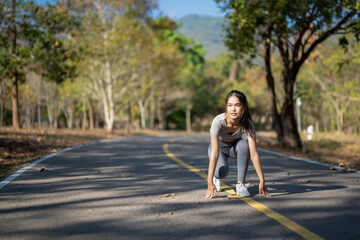 Fototapeta premium A woman is running on a road with trees in the background