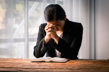 Hands folded in prayer on a Holy Bible in church concept for faith, spirituality and religion,...