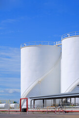 White storage fuel tanks with oil pipeline system on the ground in industrial refinery yard area...
