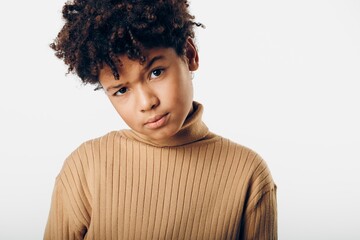 Portrait of a young african american boy in a cozy brown turtleneck sweater against a pristine white background