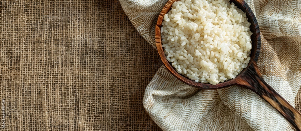 Wall mural Rice and grits displayed on textured fabric with a wooden spoon providing a background for text in this copy space image