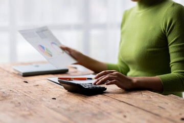 Woman accountant use calculator and computer with holding financial graph data analysis and project management concept, 