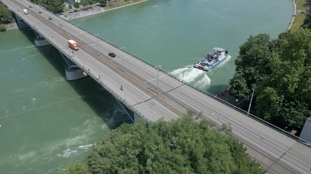 4K Drone Video of Tugboat Pulling Oil Barge Under the Wettsteinbr&uuml;cke Bridge over the Rhine River in Basel, Switzerland